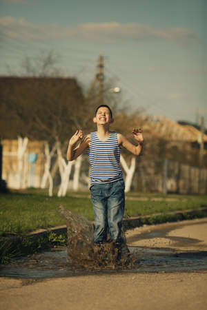 little happy boy standing in puddleの写真素材
