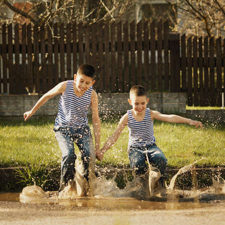 little happy boy standing in puddleの写真素材