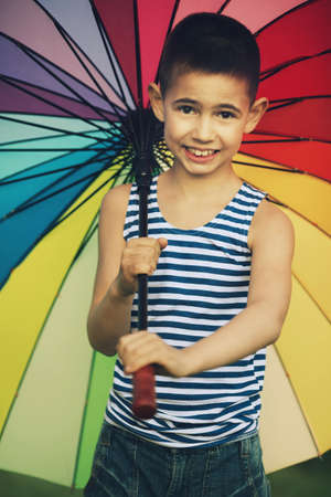 little happy girl with a rainbow umbrella in parkの写真素材