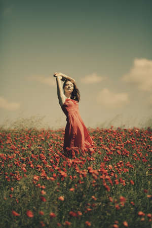 young red haired beautiful girl in poppy fieldの写真素材