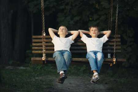 little boys riding on swingの写真素材