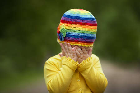 little girl with rainbow hat is playing hide-and-seek