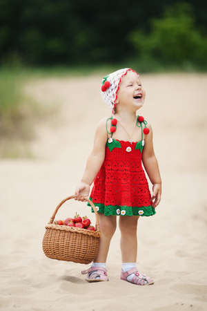 little happy girl with basket full of strawberriesの写真素材