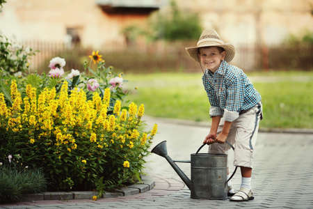 cute little boy watering flowers watering canの写真素材