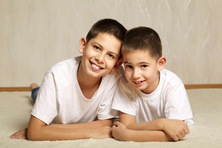 Cheerful brothers lying on floorの写真素材