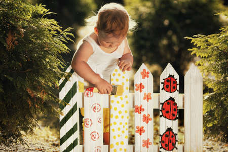 little cute girl paints fenceの写真素材
