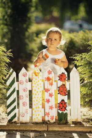 little cute girl paints fenceの写真素材