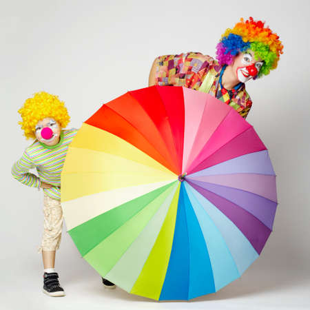 funny clown with colorful umbrella on whiteの写真素材
