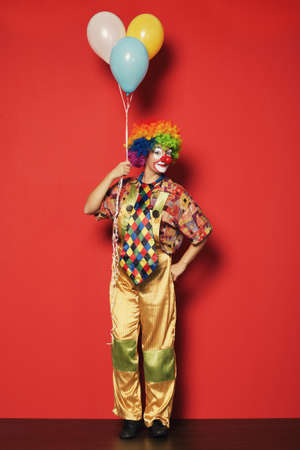 funny clown with balloons on red backgroundの写真素材
