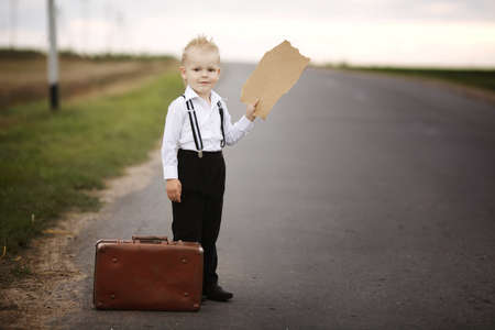 boy hitch hiking at road holding cardboardの写真素材