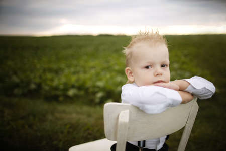 little boy sits on chair in the fieldの写真素材