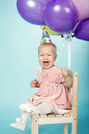 unhappy little girl with cap and balloons