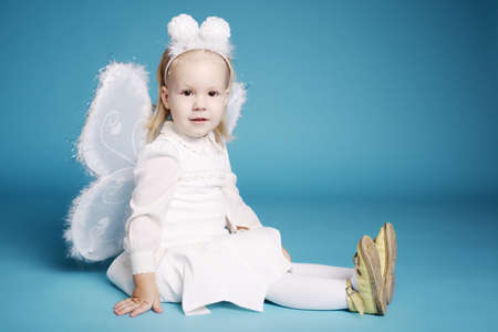 Cute little girl with butterfly costume on blue wallの写真素材