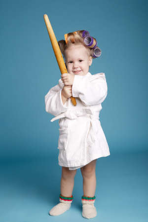 young housewife with rolling pin on blue wallの写真素材