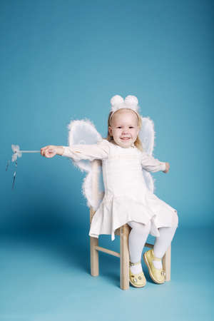 Cute little girl with butterfly costume on blue wallの写真素材