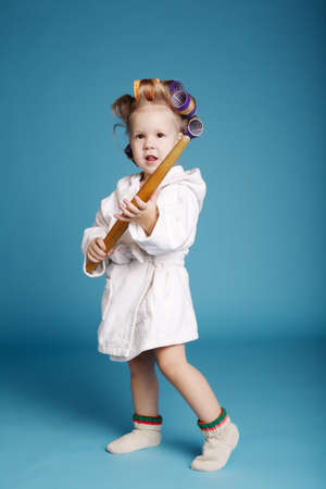 young housewife with rolling pin on blue wallの写真素材