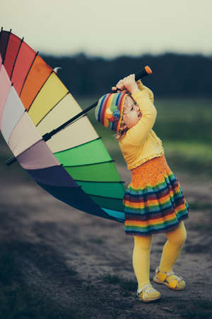 little girl with rainbow umrella in the fieldの写真素材