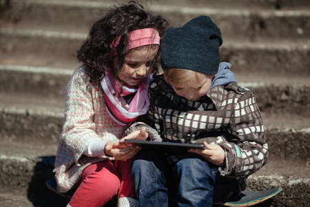 boy and girl using tablet together outdoorsの写真素材