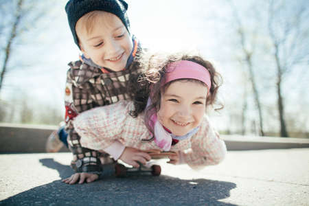 little cute boy and pretty girl skaiting on the street