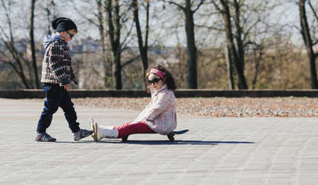little boy and girl skating on the streetの写真素材