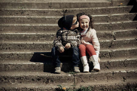 litle happy boy kissing girl on stairwayの写真素材