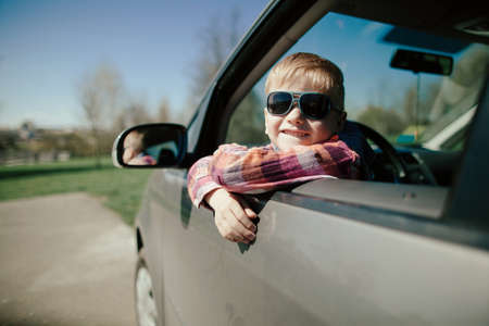 little cute boy driving fathers car at springtimeの写真素材