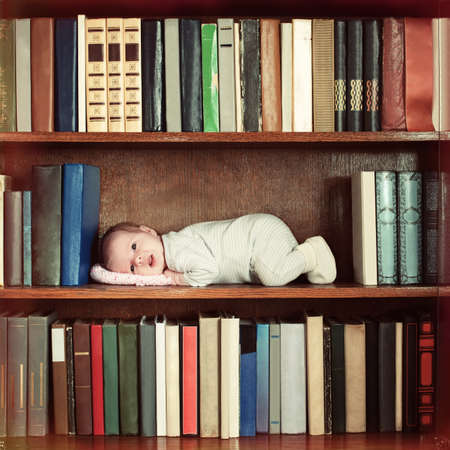 baby lying on book shelf in bookcaseの写真素材