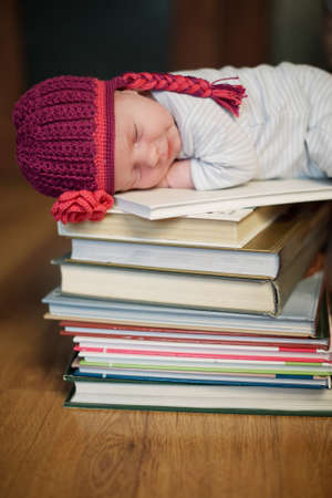 baby sleeping on stack of booksの写真素材