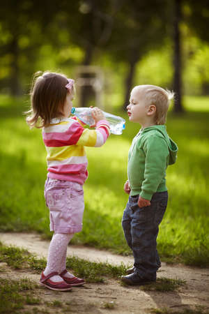 boy and girl drinking mineral water in parkの写真素材