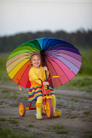 little cute girl on the bicycle with umbrella in her handsの写真素材