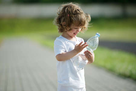 little beautiful girl drinking clean water from plastic bottleの写真素材