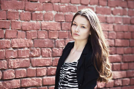 beautiful girl near red brick wall portraitの写真素材