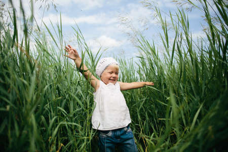 happy little girl in high grass photoの写真素材