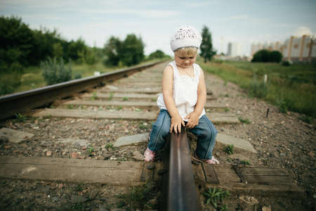 little beautiful girl plays on railroad photoの写真素材
