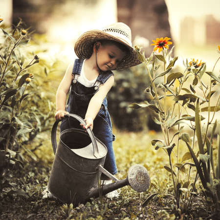 cute little boy with watering can in summer parkの写真素材