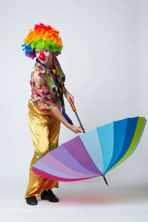 funny clown with colorful umbrella on whiteの写真素材