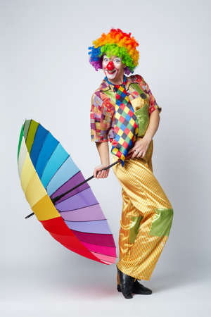 funny clown with colorful umbrella on whiteの写真素材
