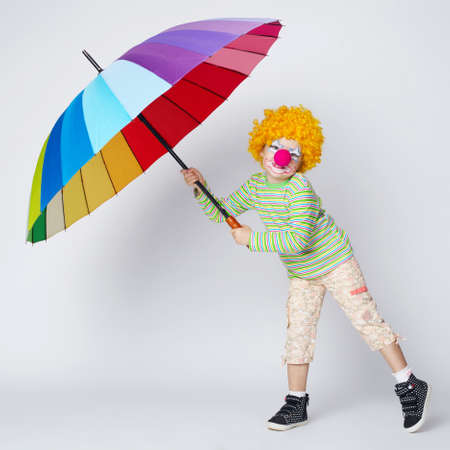 funny clown with colorful umbrella on whiteの写真素材