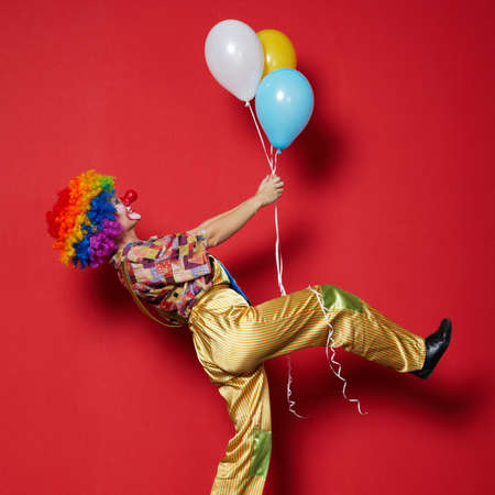 funny clown with balloons on red background