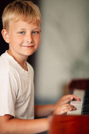 little happy boy plays piano at homeの写真素材