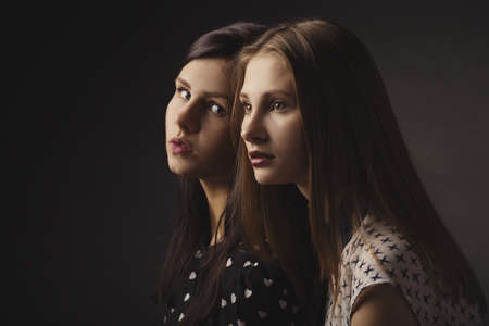 two girls studio portrait on dark background