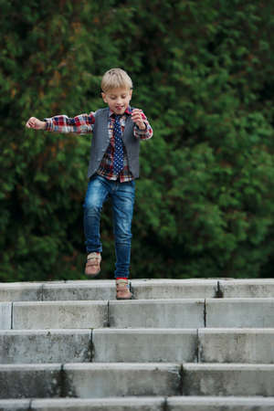 portrait of little boy jumping on the stairsの写真素材