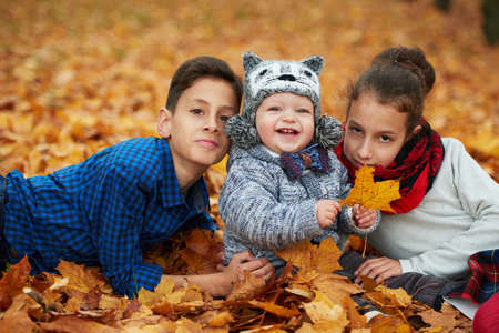boys and girl among the leaves in autumn parkの写真素材