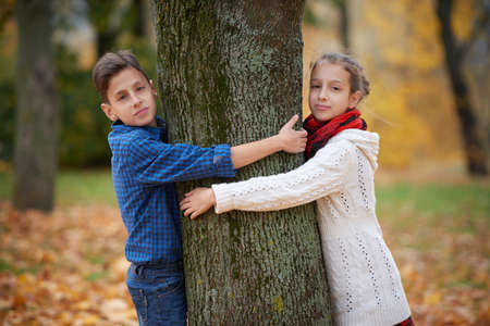 boy and girl among the leaves in autumn parkの写真素材