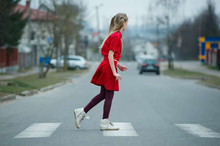 photo of girl crossing street on the crosswalk