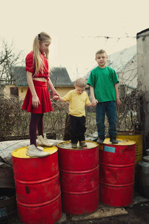 children play at dump drums of oilの写真素材