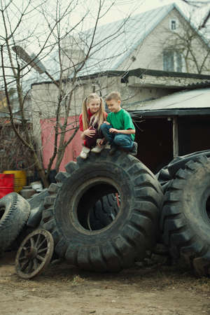 photo of happy children playing in junkyard tires
