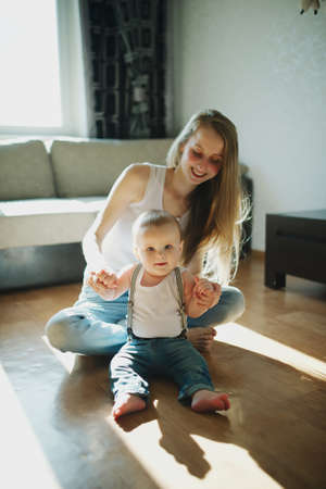 young beautiful mother with baby sitting on the floor