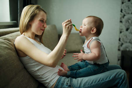 young mother feeding baby with a spoonの写真素材