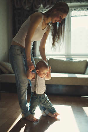 young beautiful mother teaches baby to walk